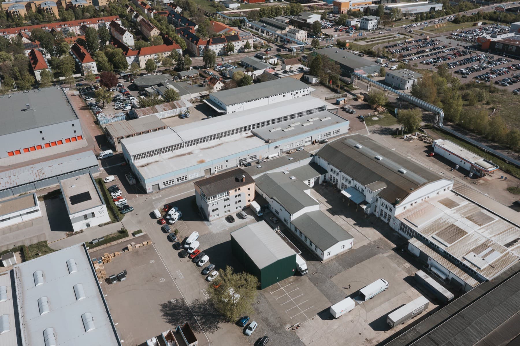 Drohnenaufnahme des 1A Gewerbeparks Halle (Saale) mit Hallen, Innenhöfen und Stadtteil im Hintergrund