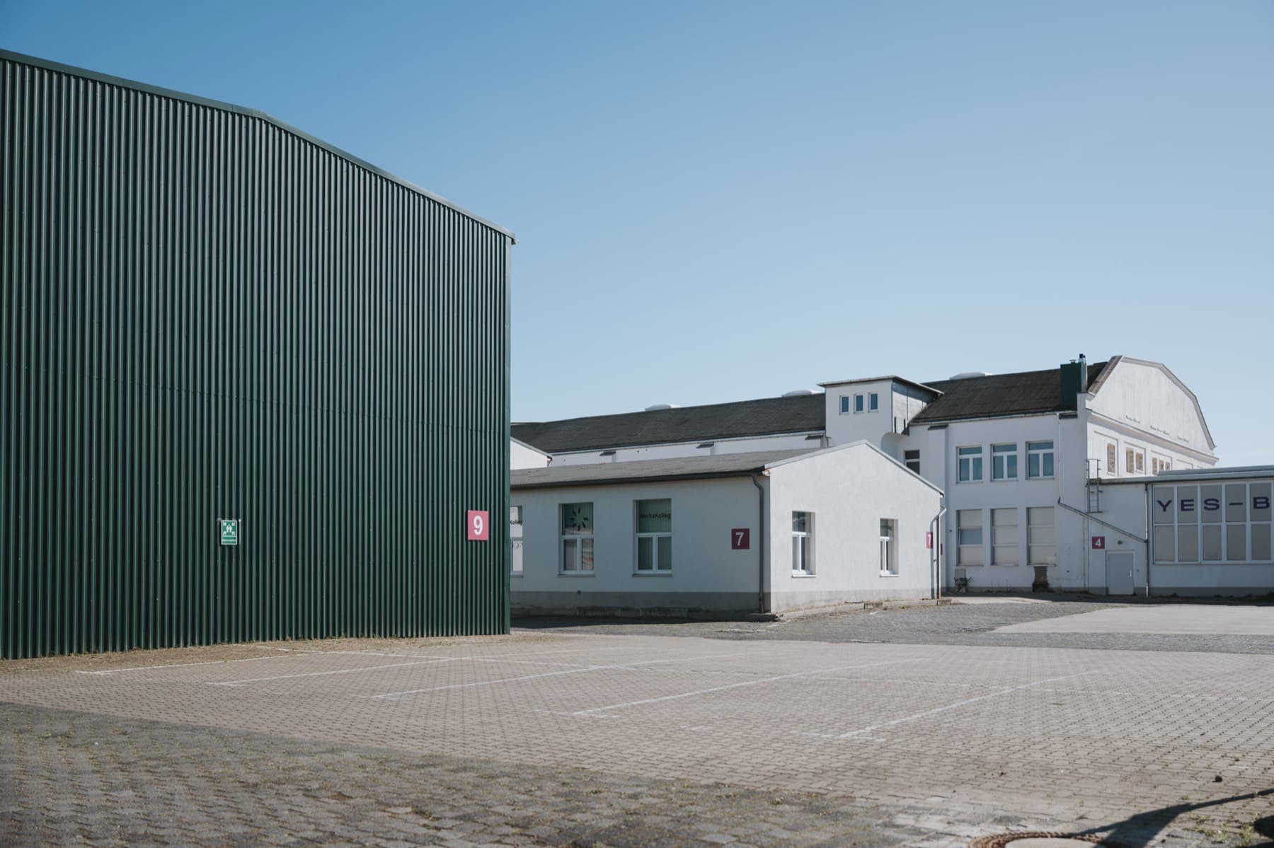 Innenhof des Gewerbeparks mit grüner Fassade der Halle 9 und den weißen Hallen 7 und 4