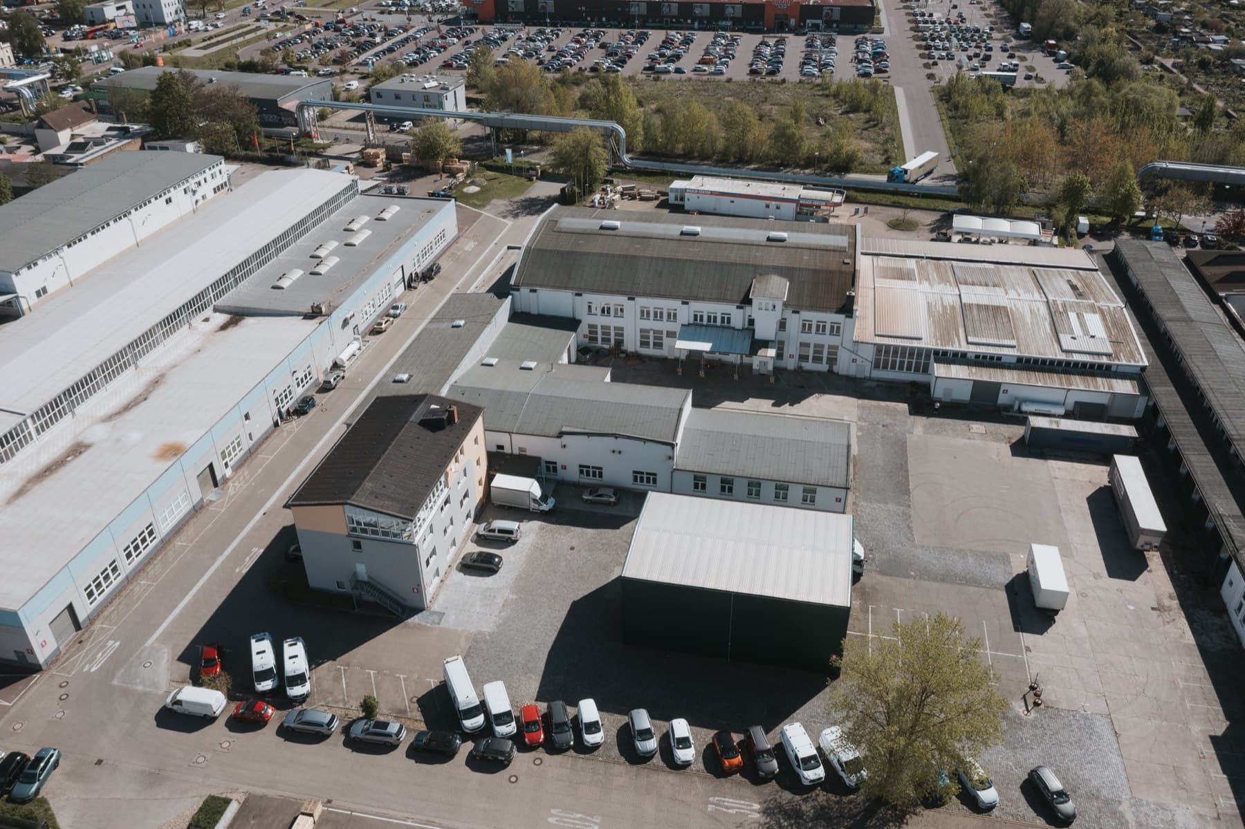 Luftaufnahme des zentralen Hofbereichs mit Hallen, Bürohaus und Fernwärmetrasse