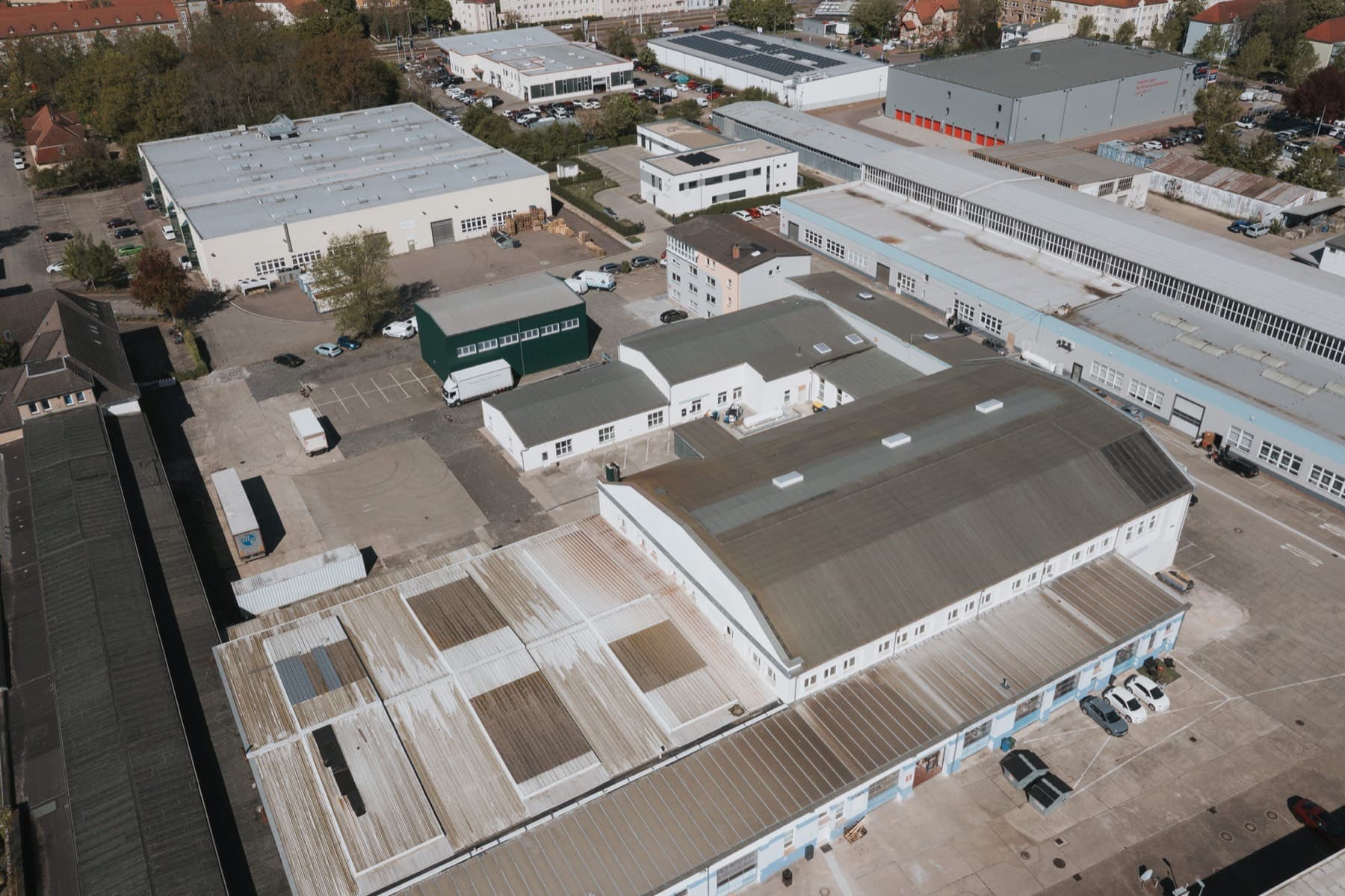 Steiler Drohnenblick auf Hallen, Stellflächen und Lieferverkehr im Gewerbepark