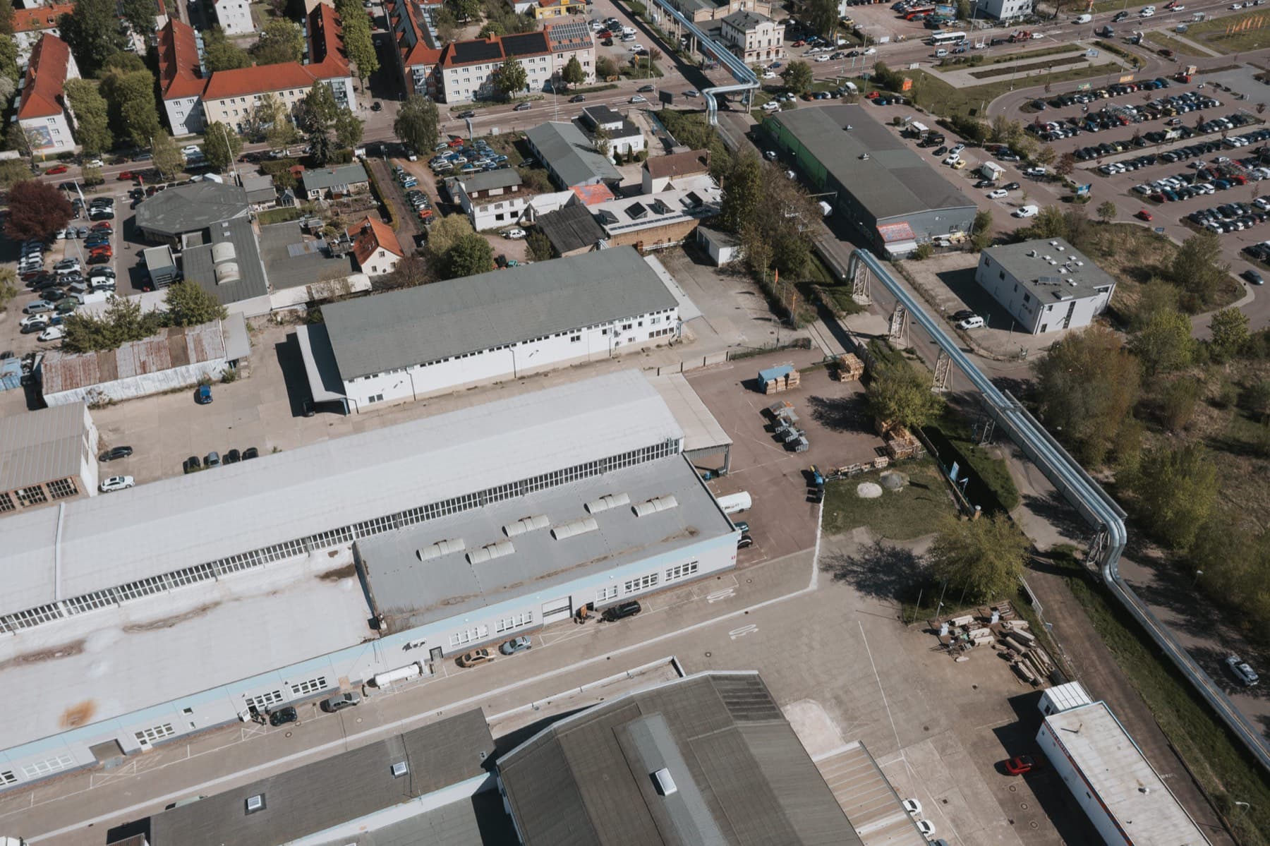 Luftaufnahme der Hallen mit Rangierflächen, Fernwärmeleitung und angrenzendem Wohngebiet