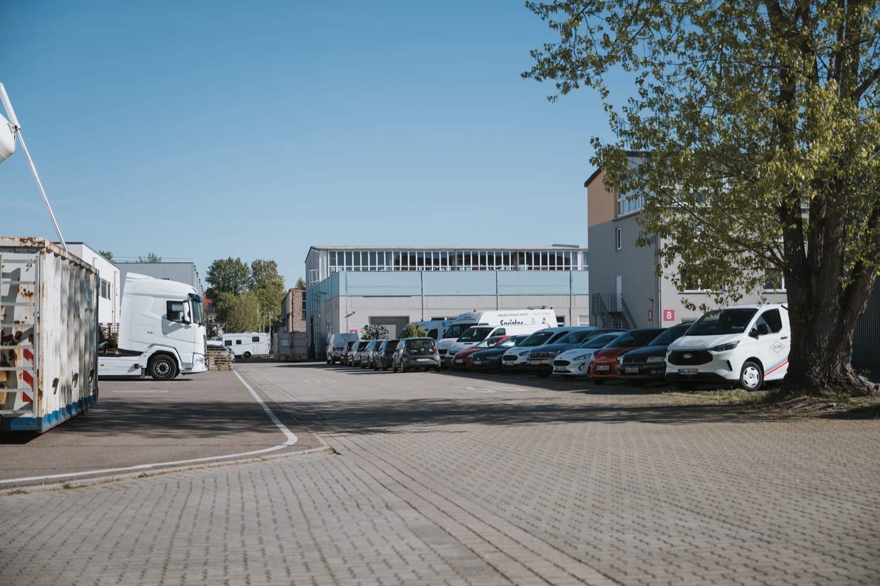 Innenstraße des Gewerbeparks mit parkenden Firmenfahrzeugen und Halle 10 im Hintergrund