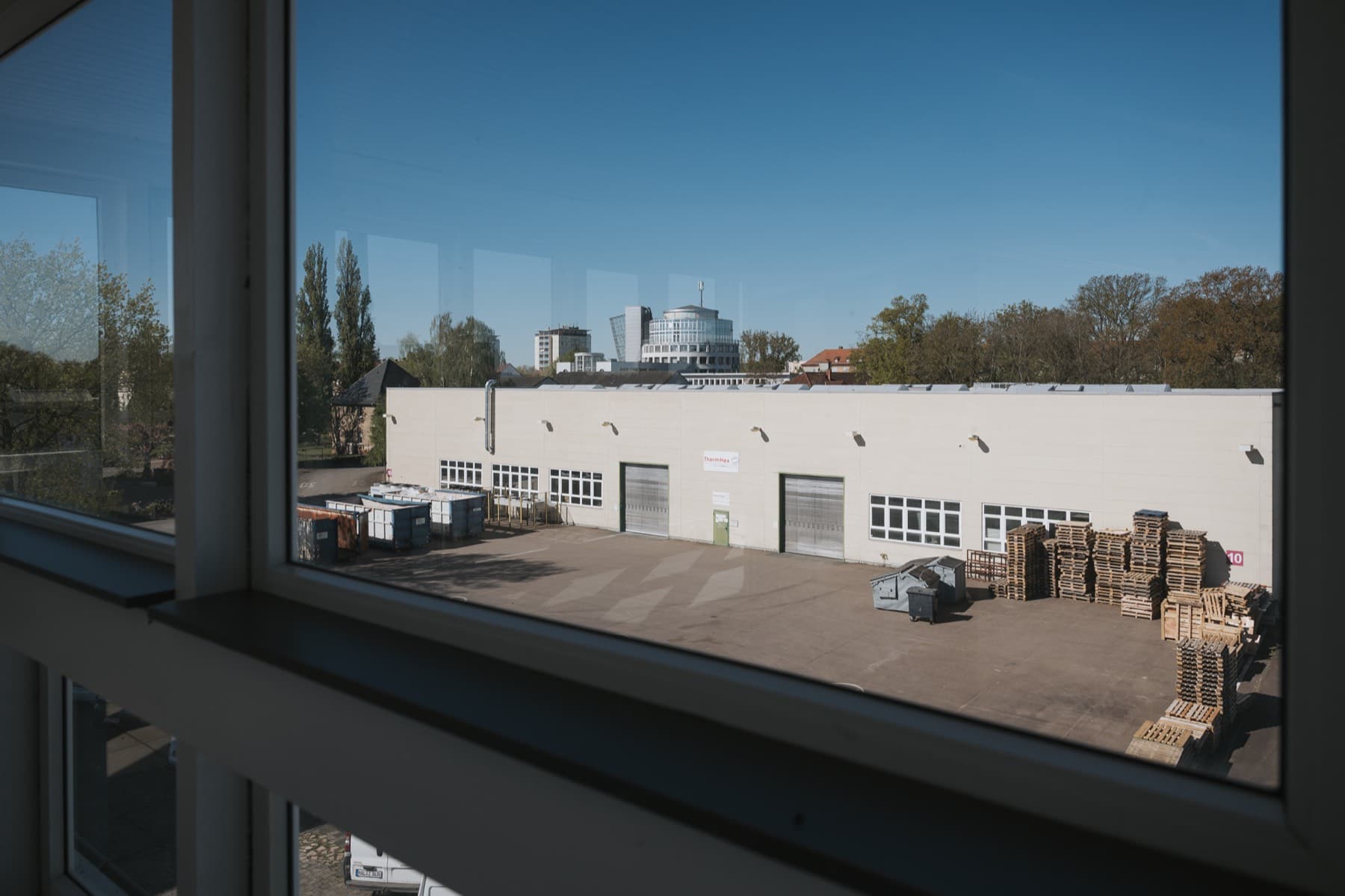 Ausblick aus dem Bürofenster von Gebäude 8 auf Halle 10 und die Stadtsilhouette