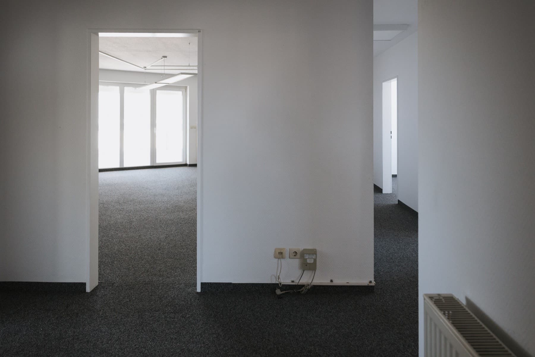 Blick durch die Bürofläche auf den lichtdurchfluteten Raum mit großer Fensterfront