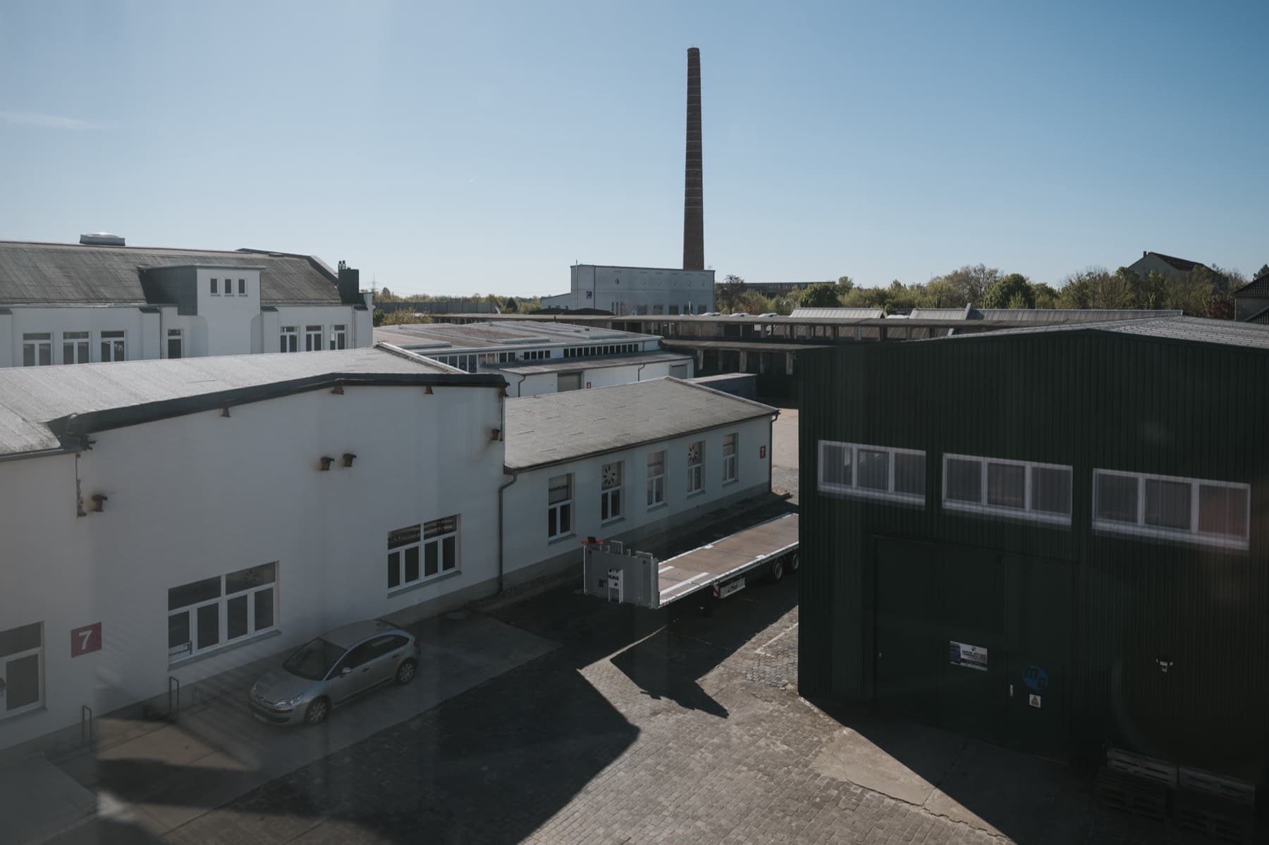 Blick von Gebäude 8 über die Hallen des Gewerbeparks mit historischem Schornstein
