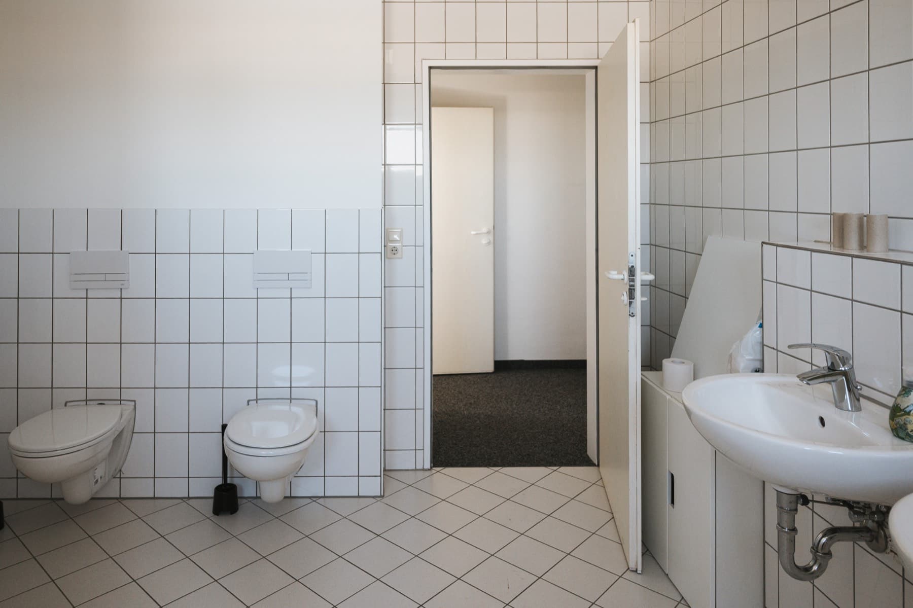 Neu gefliester Sanitärbereich mit WCs und Waschbecken im Gebäude 8