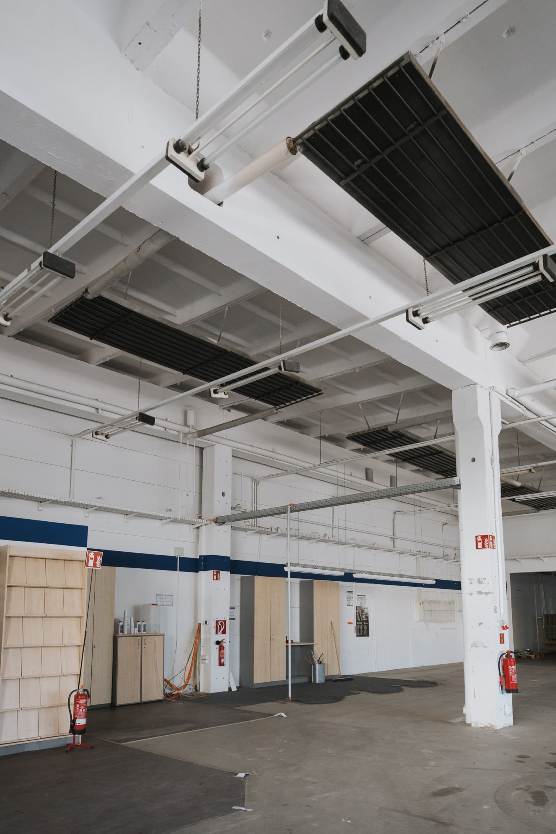 Halle 1 — Innenansicht mit weißen Betonstützen, hoher Decke und Einbauschränken an der Wand