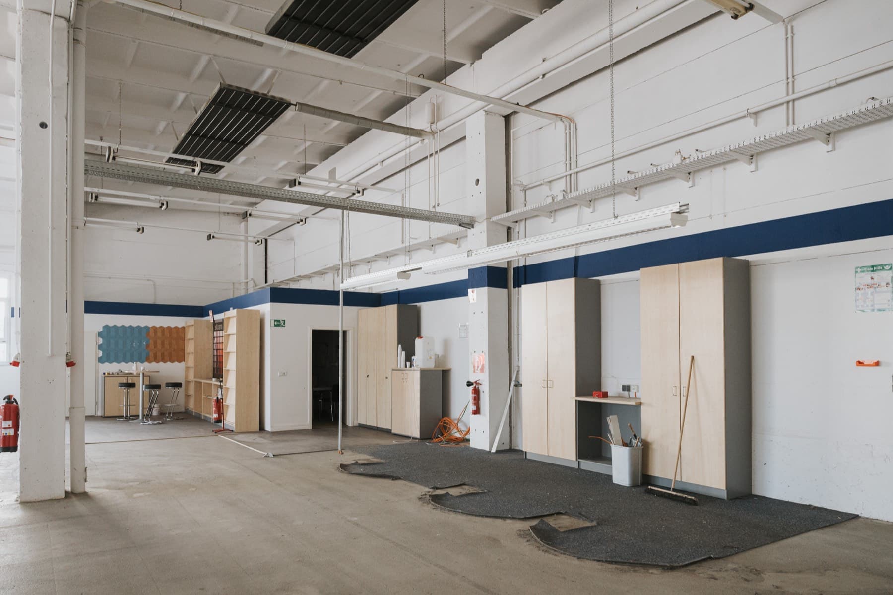 Halle 1 — großer Innenraum mit weißer Stütze, hoher Decke und Schrankzeile an der Wand