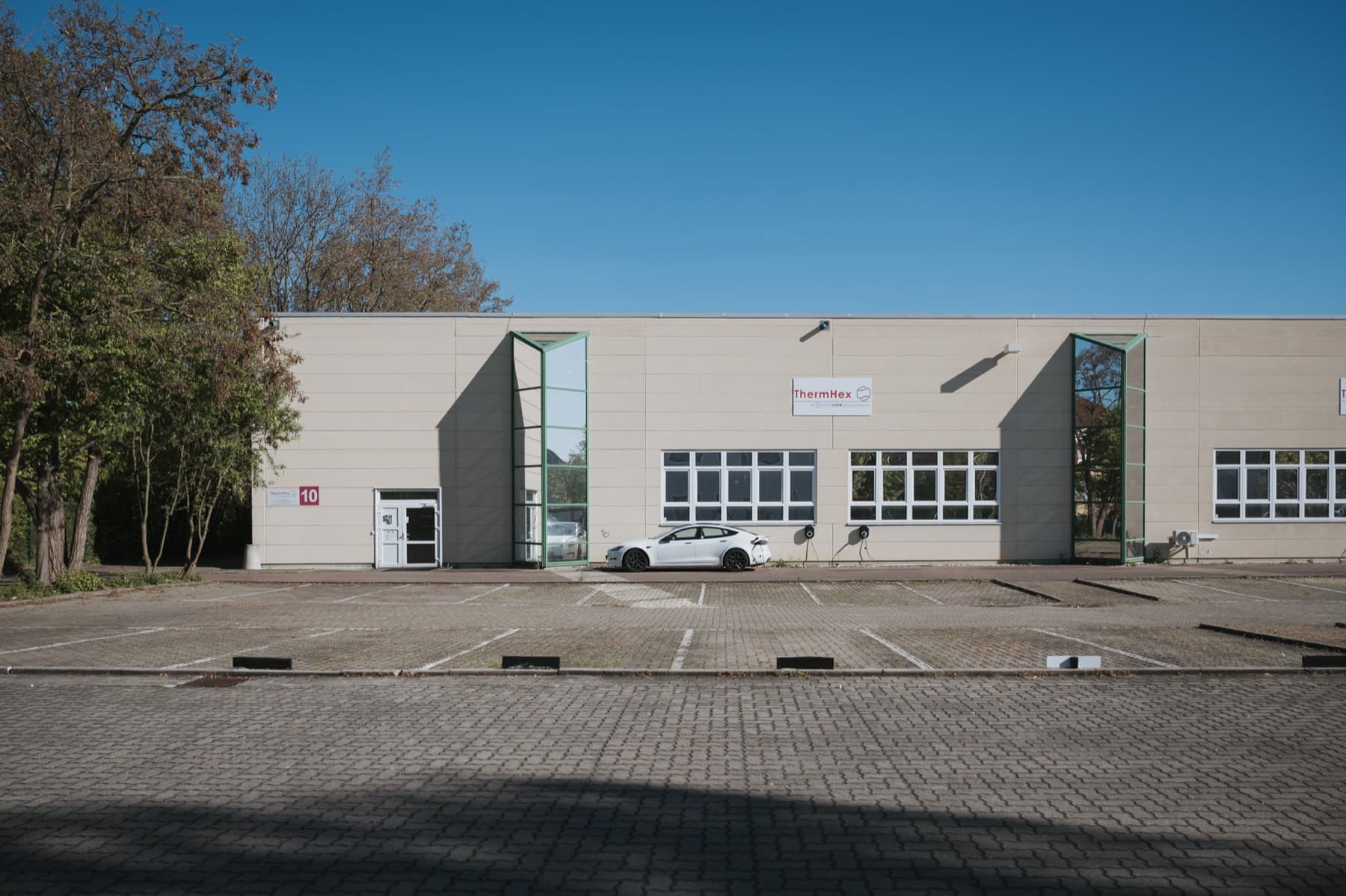 Frontansicht der Halle 10 mit ThermHex-Firmenschild, Hallennummer und ladendem Elektroauto
