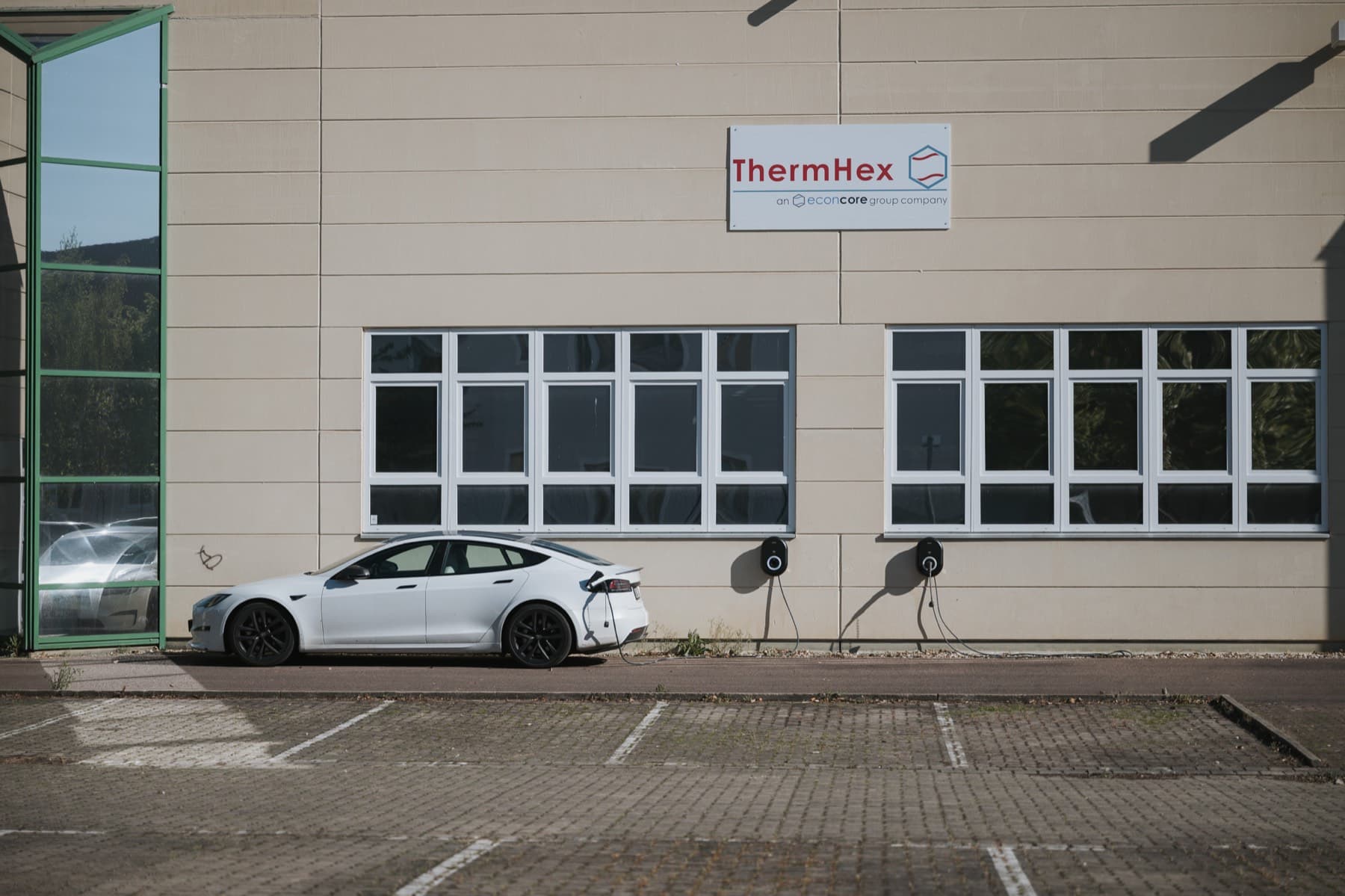 Elektroauto lädt an der Wallbox vor der Fassade der Halle 10 mit ThermHex-Schild