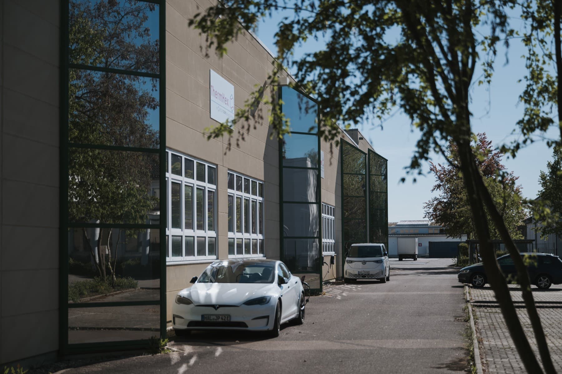 Zwei Elektrofahrzeuge an den Wallboxen entlang der Fassade der Halle 10