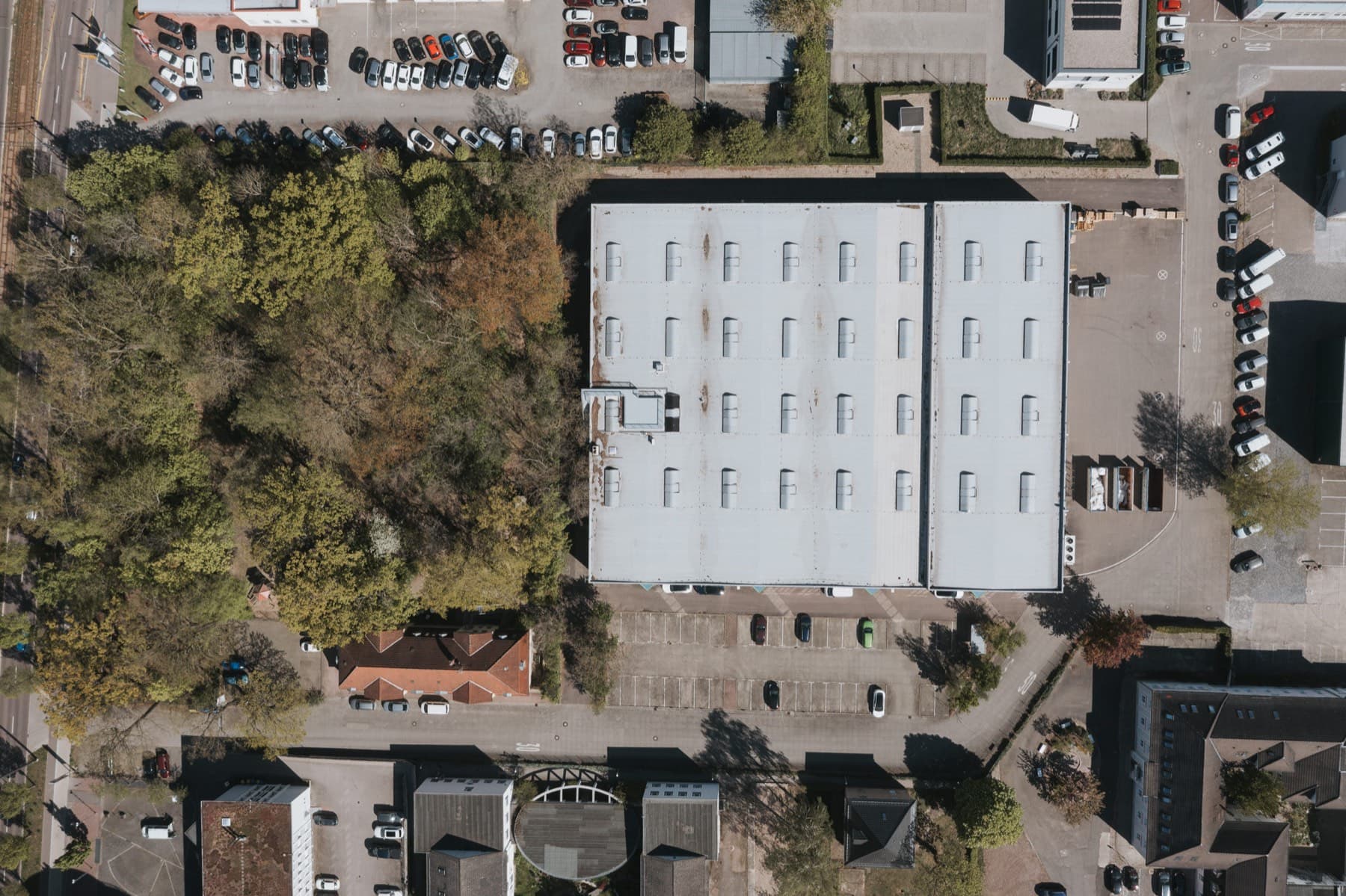 Senkrechte Drohnenansicht der Halle 10 mit Dachfläche, Stellplätzen und Grünstreifen