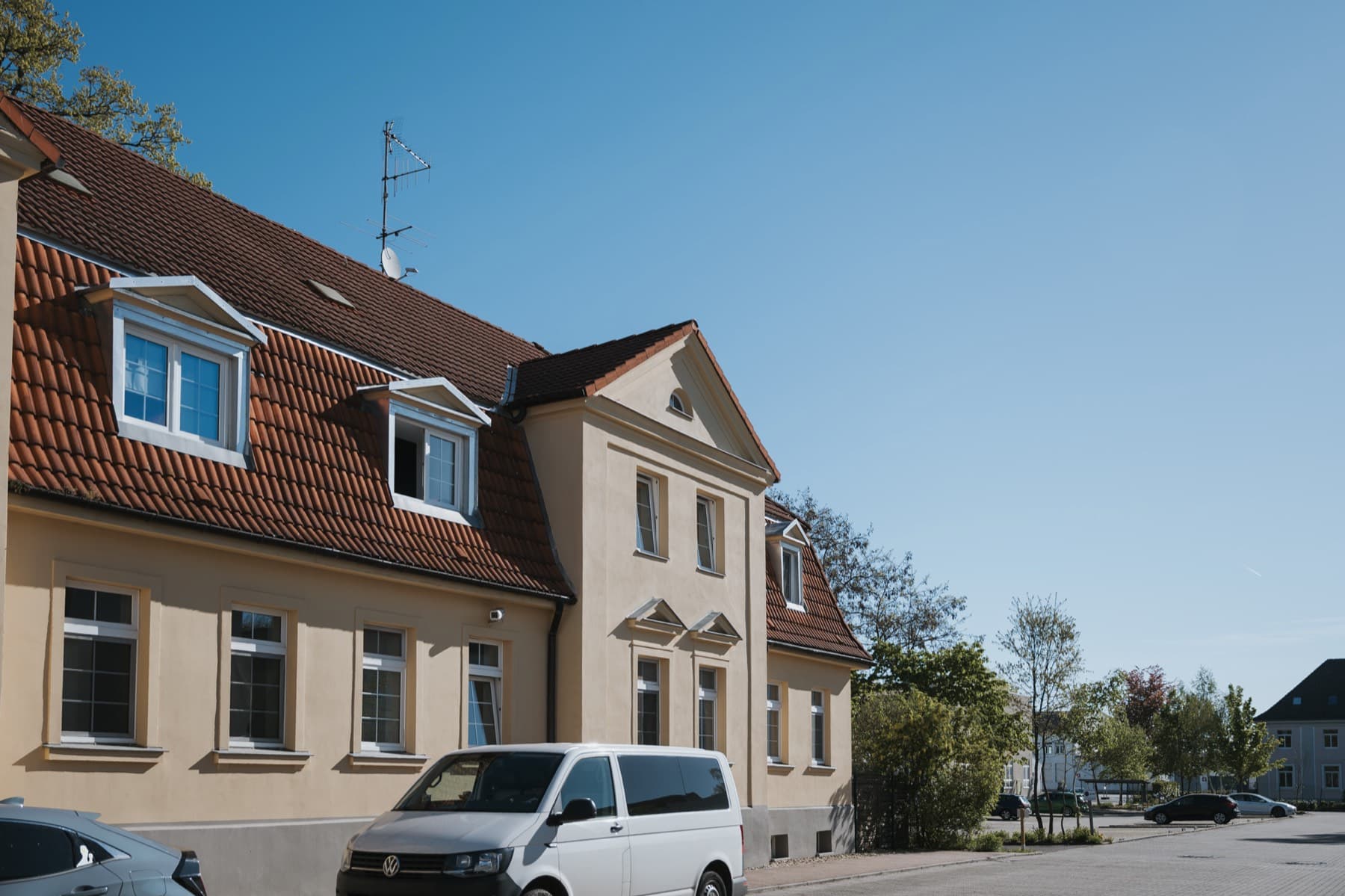 Halle 11 — Fassade mit Gaubenfenstern und Stuckgiebel, davor parkender Transporter