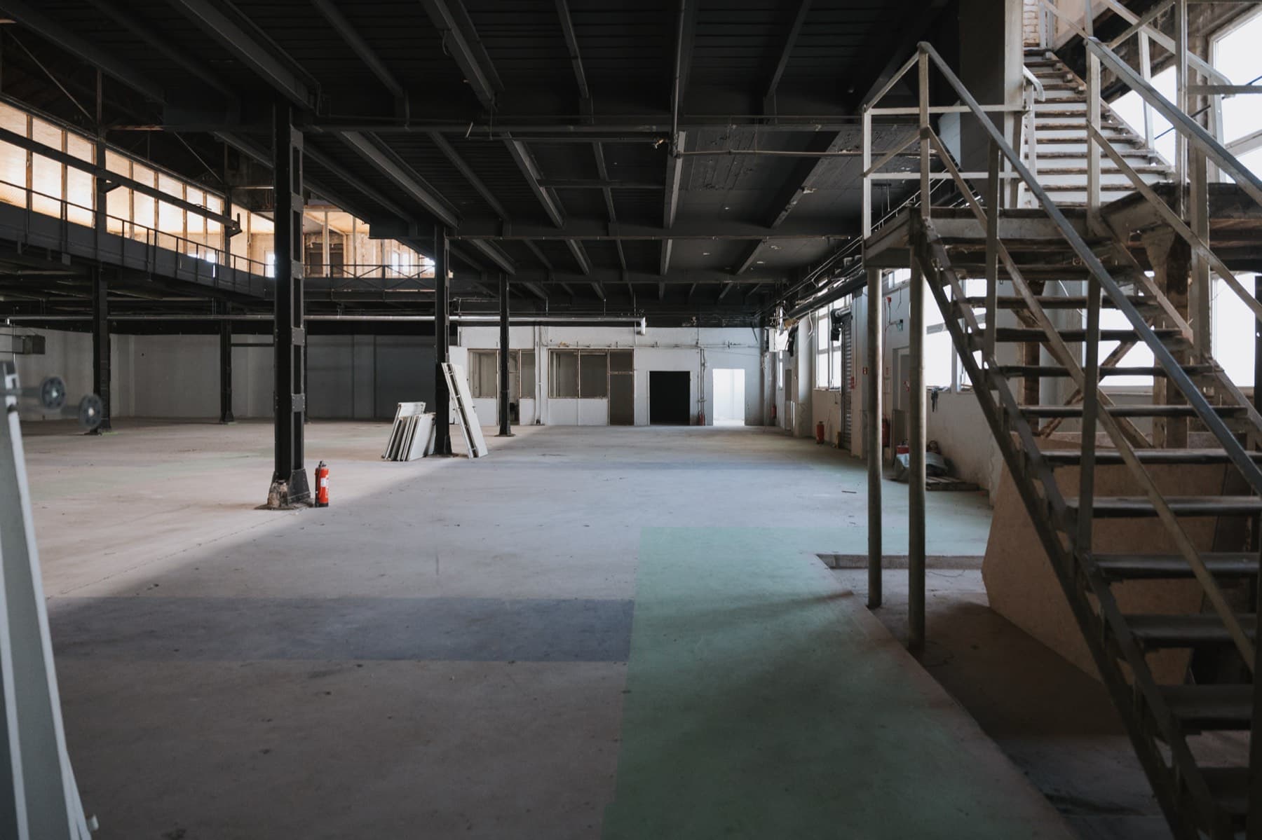Weite Industriehalle in Halle 2 mit schwarzer Stahlkonstruktion, umlaufender Galerie und Stahltreppe