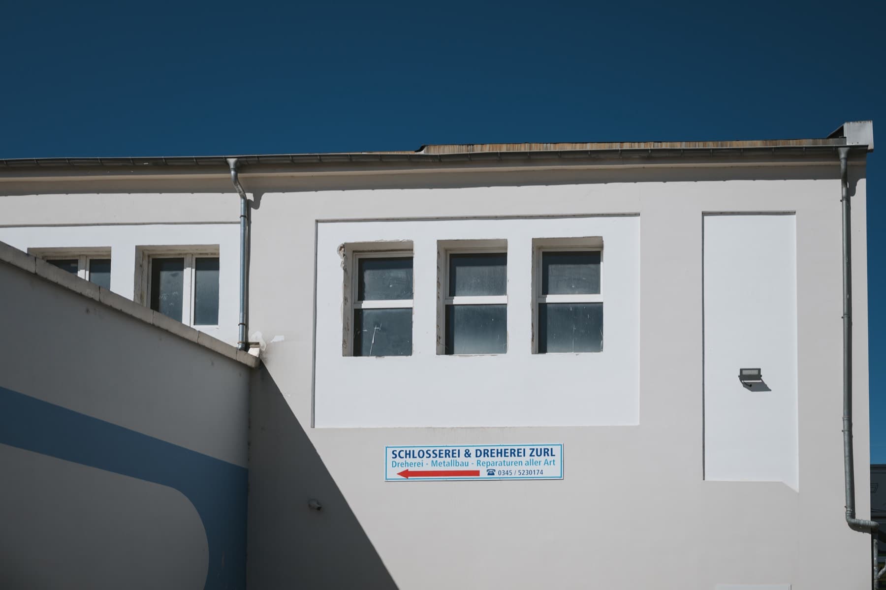 Helle Außenfassade der Halle 2 mit Firmenschild der Schlosserei & Dreherei Zurl