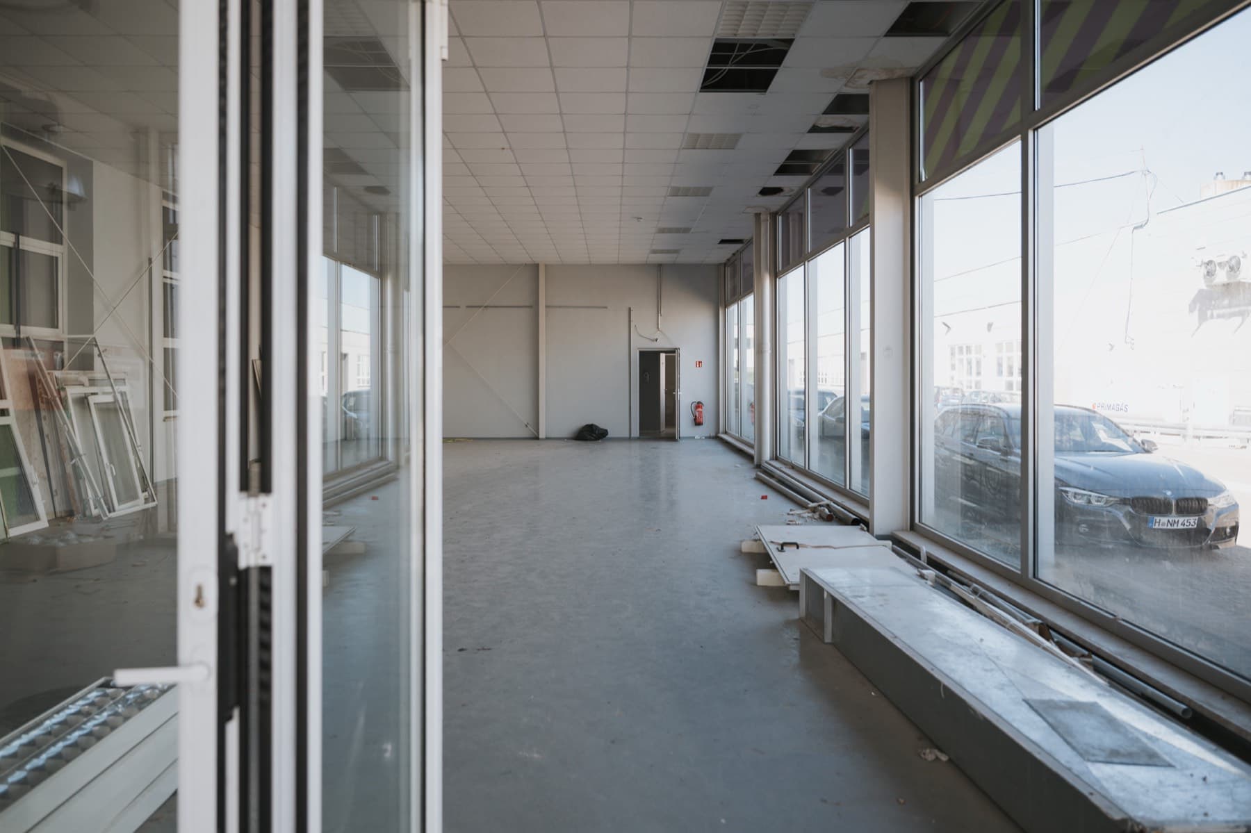 Leere Gewerbefläche mit raumhoher Glasfront und Blick auf den Parkplatz in Halle 2