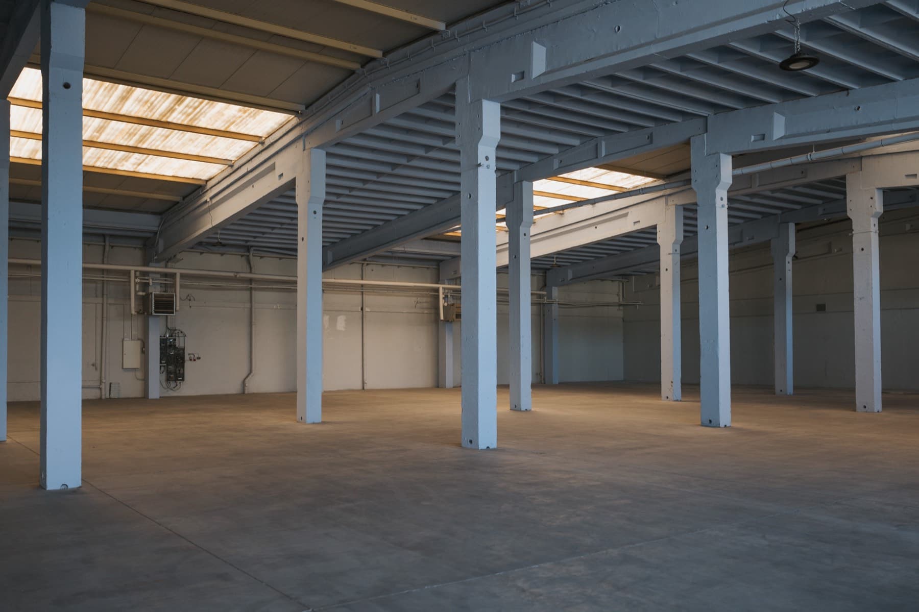Helle, leere Hallenfläche der Halle 4 mit Oberlichtern und Stützenraster