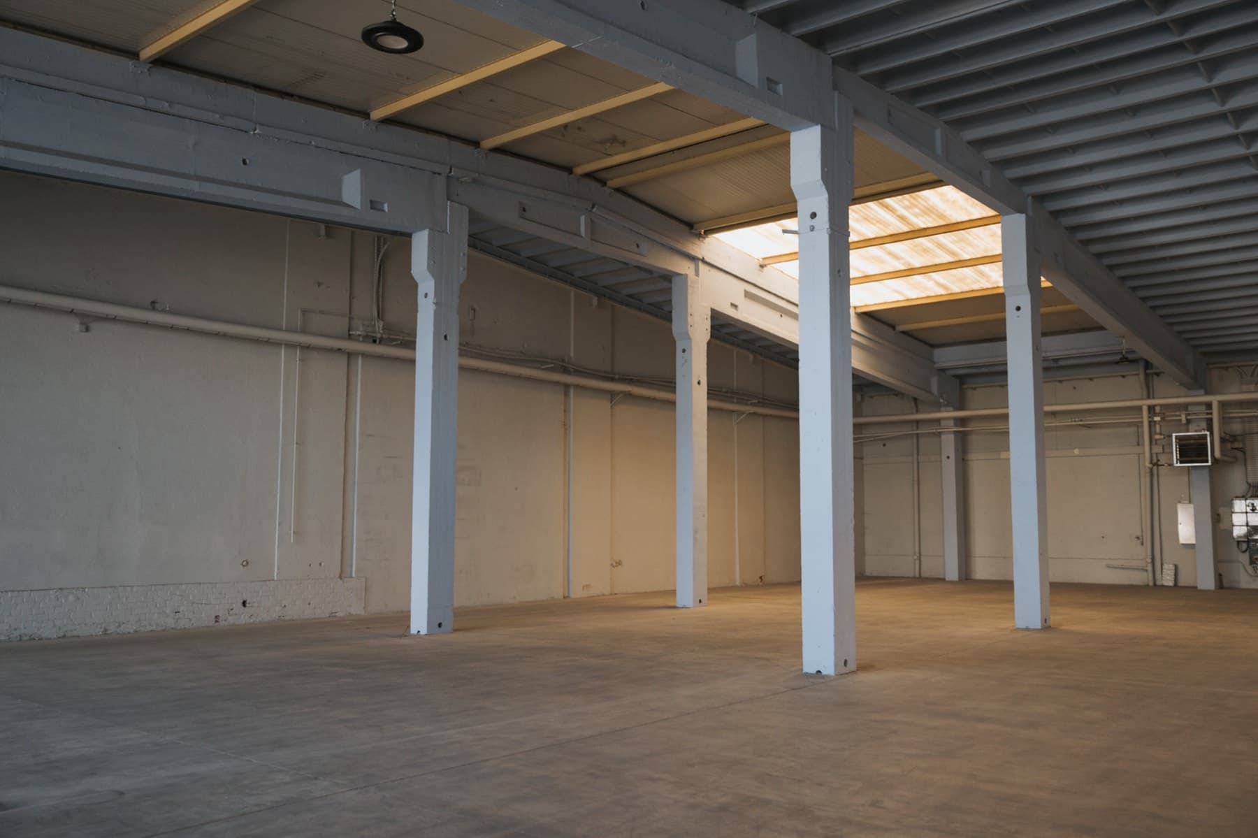 Zentralperspektive durch die leere Halle 4 mit Lichtbändern im Dach