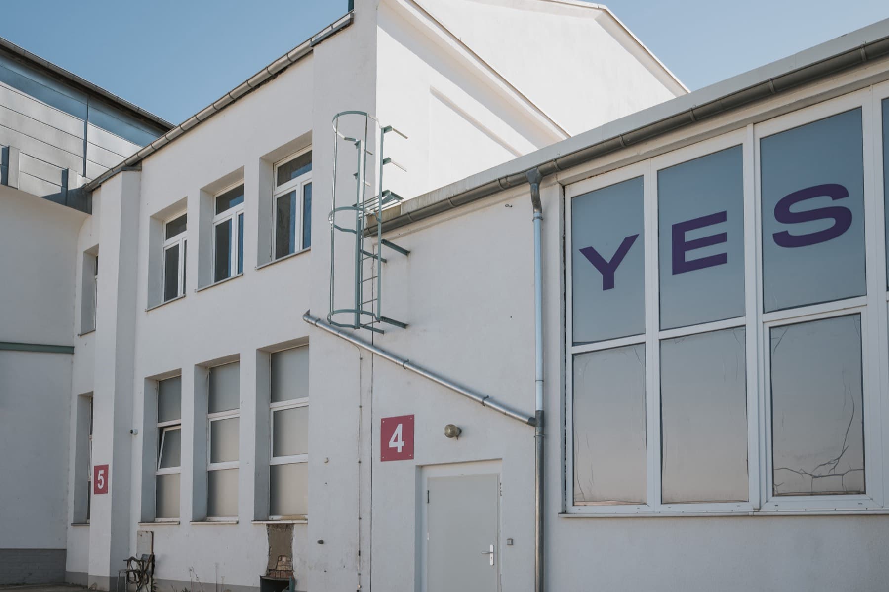 Gebäudeecke der Halle 4 mit YES-BOX-Fensterfront und Hallenschildern