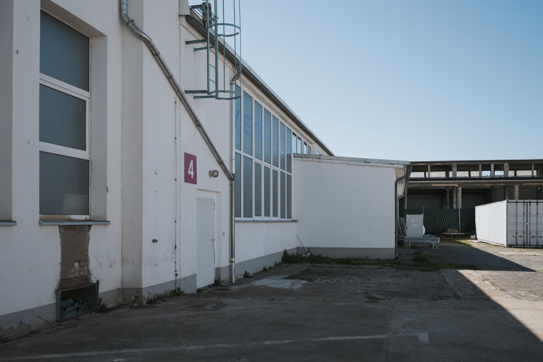 Hofseite der Halle 4 mit rotem Hallenschild und Fensterband